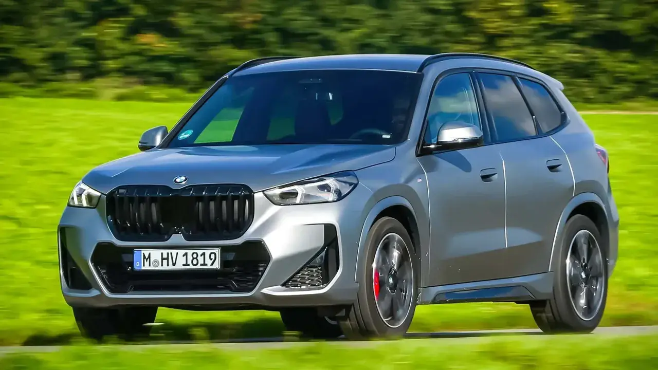 Grauer BMW X1 xDrive23d fährt auf einer grünen Wiese. Keine Probleme sichtbar, nur Fahrspaß.