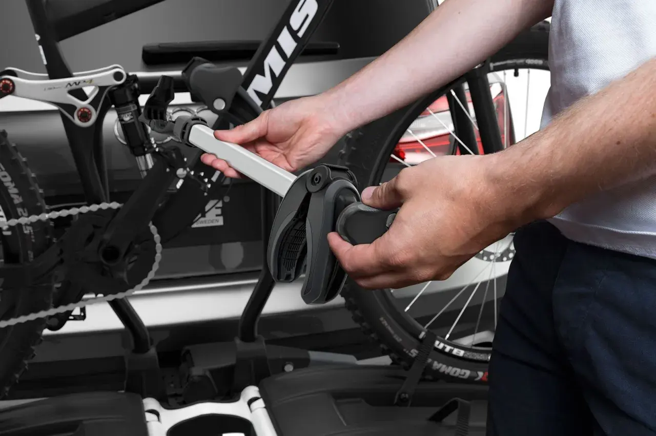 Hände montieren Fahrrad am Thule EasyFold XT 2. Ein Griff klemmt, was auf Thule EasyFold XT 2 Probleme hindeuten könnte.