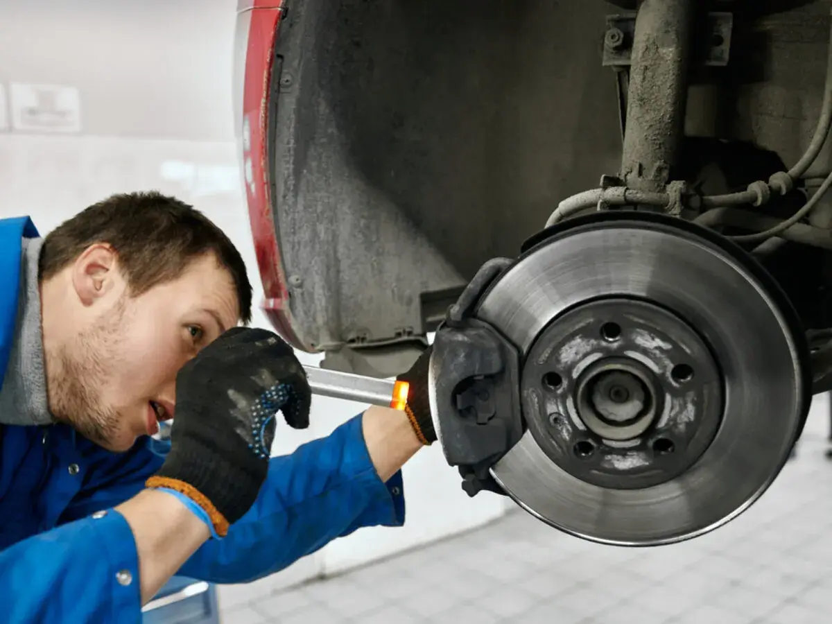 Mechaniker prüft die **bremse auto links oder rechts**. Er arbeitet am Bremssattel und der Bremsscheibe.