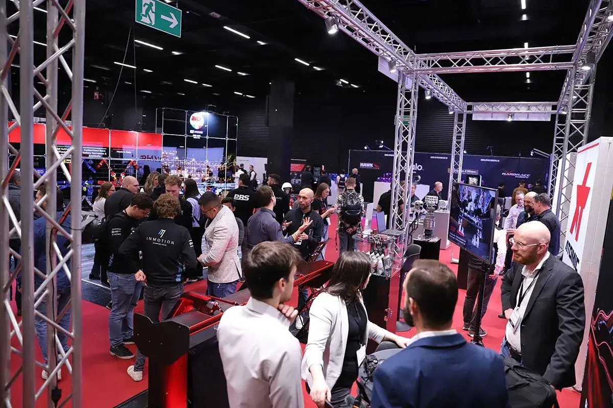 Besucher auf der Professional Motorsport World Expo, die sich über Rennsporttechnologie informieren.