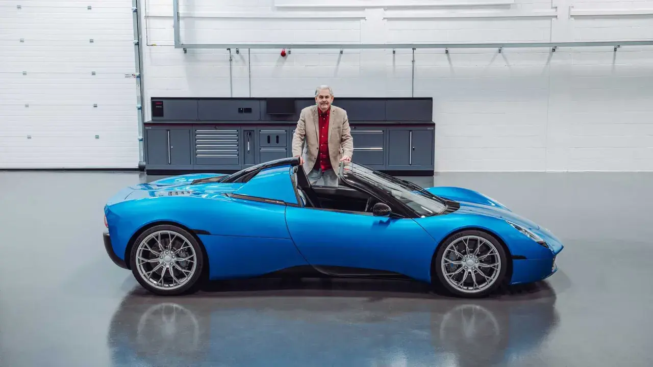 Gordon Murray präsentiert stolz seinen neuen Gordon Murray T.33, einen leuchtend blauen Supersportwagen in einer Werkstatt.