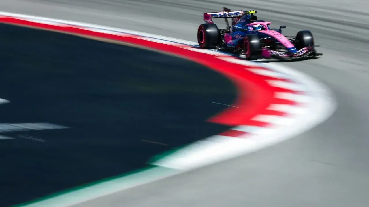 Ein Formel-1-Auto in Pink und Blau rast über die Rennstrecke. Dieses Bild fängt die Dynamik des Motorsports im TV perfekt ein.