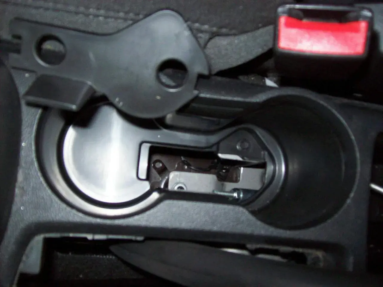 Detailaufnahme des Innenraums eines Opel Mokka, Fokus auf den Bereich um den Getränkehalter, wo das Handbremsseil gewechselt wird.