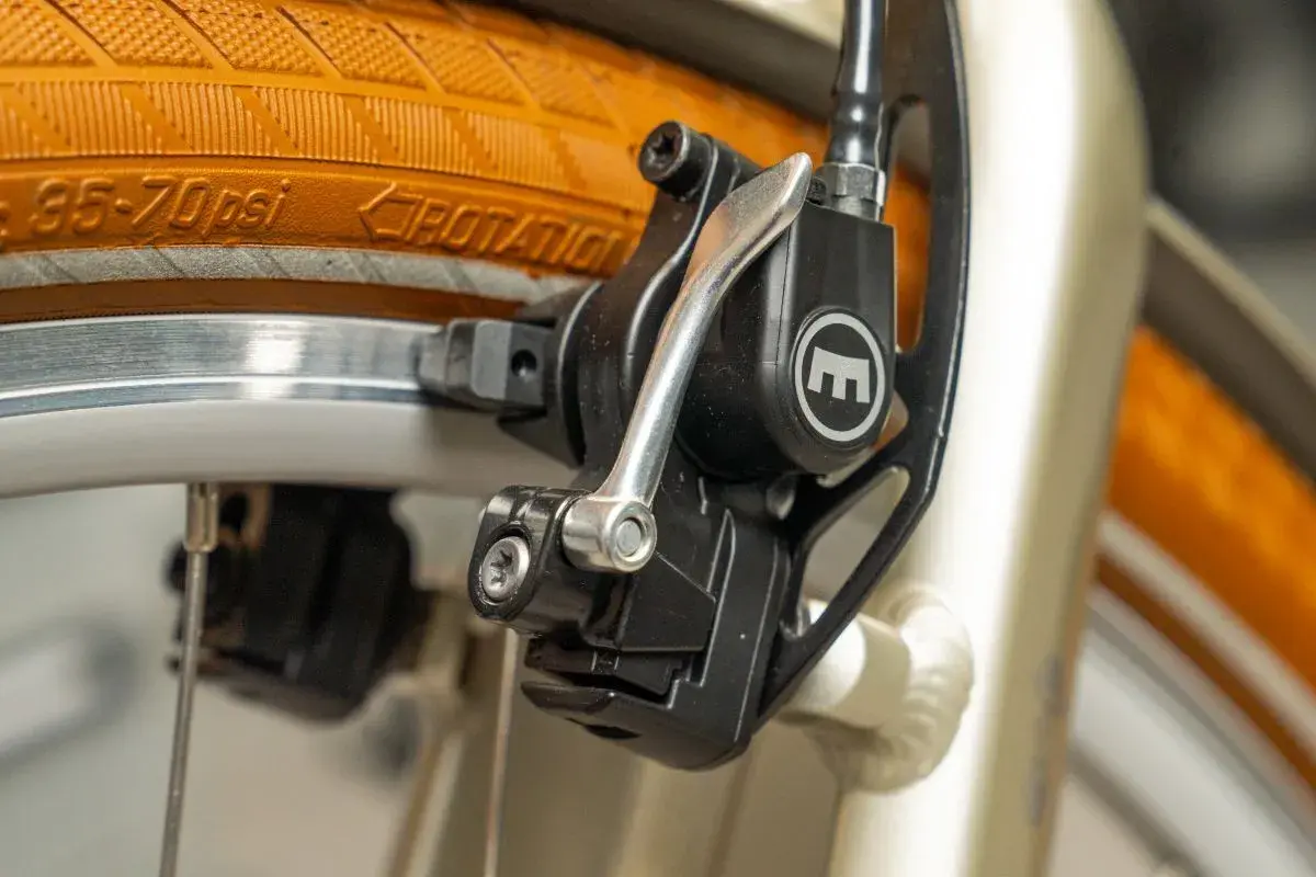 Nahaufnahme einer Fahrradbremse mit orangefarbenem Reifen und Felge.