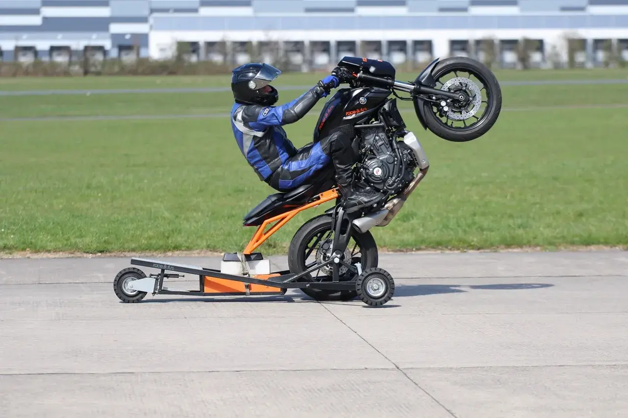 Motorradfahrer übt einen Wheelie auf einem Trainingsständer.