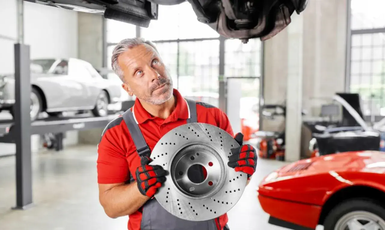 Mechaniker hält Bremsscheibe, gute febi bremsen erfahrung. Auto in Werkstatt.