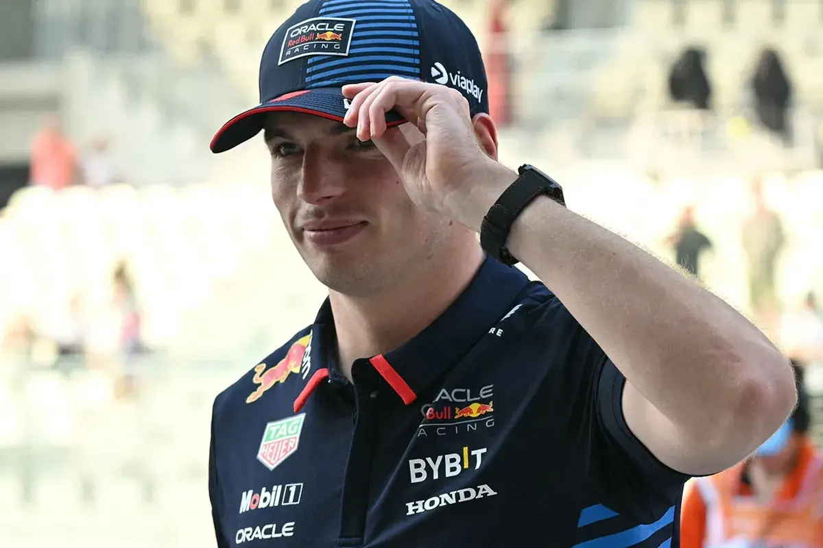 Max Verstappen in Red Bull Racing Kappe und Polo-Shirt, die Hand am Schirm.