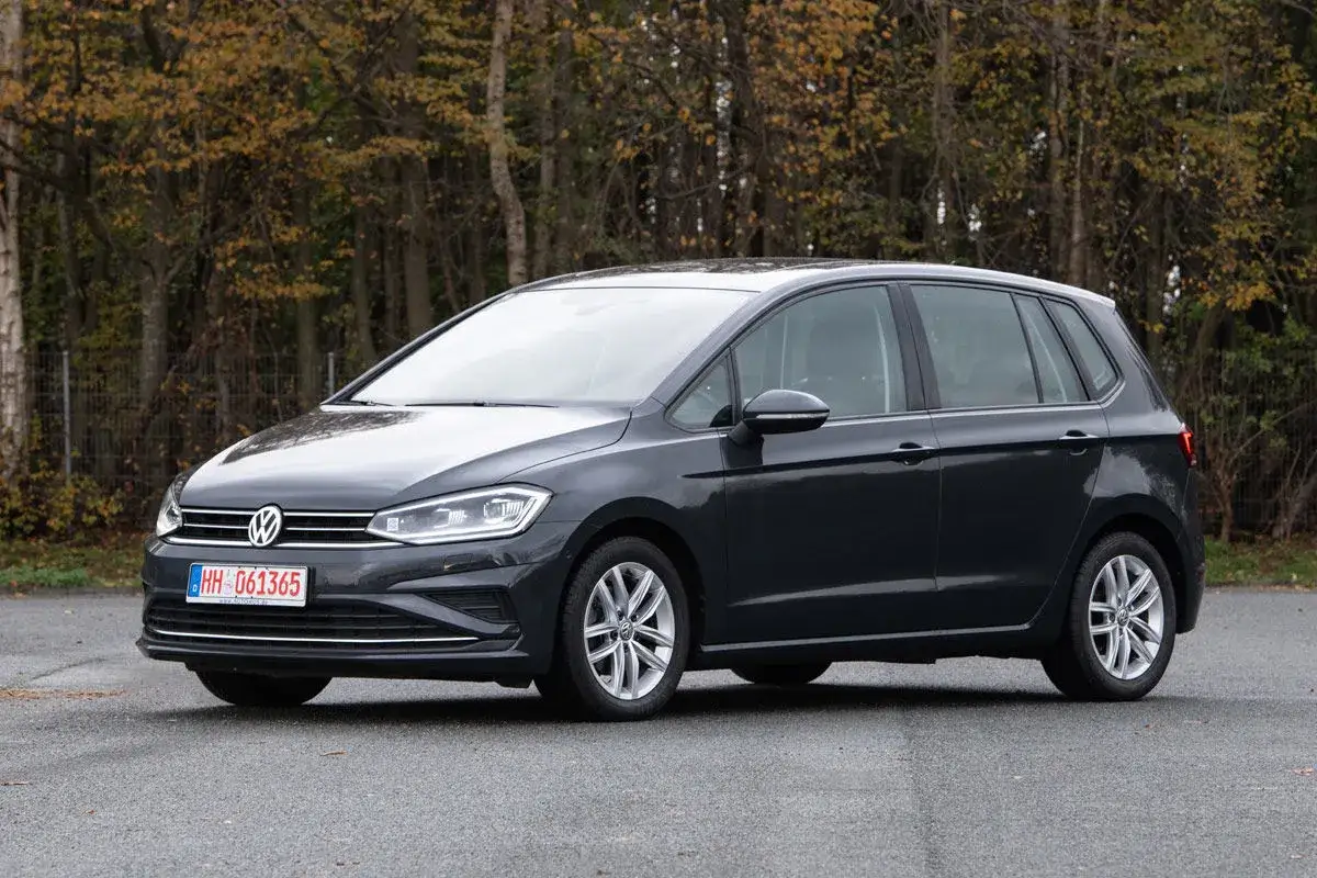 Dunkelgrauer VW Golf Sportsvan steht auf Asphalt. Herbstlaub im Hintergrund. Keine Probleme sichtbar.
