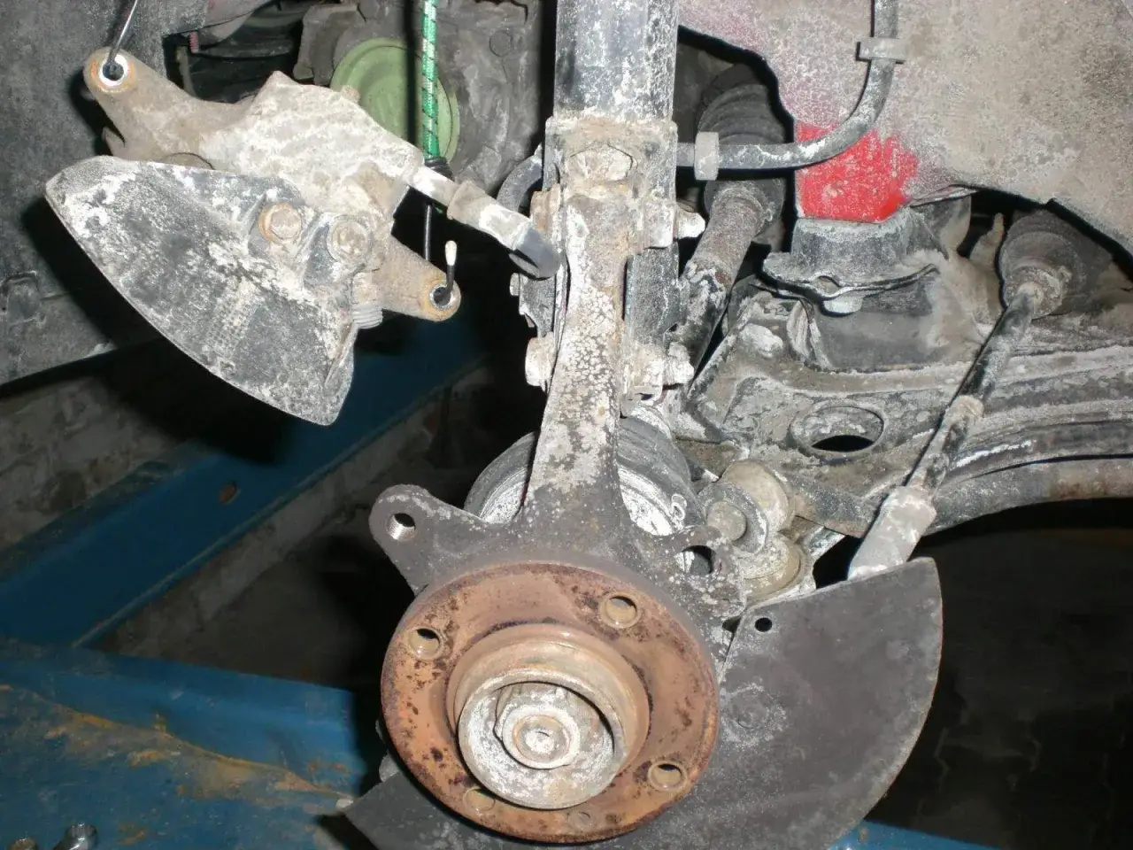 Vorderachse eines Golf 7, bereit für den Wechsel des Radlagers. Rostige Teile und eine freigelegte Radnabe sind sichtbar.