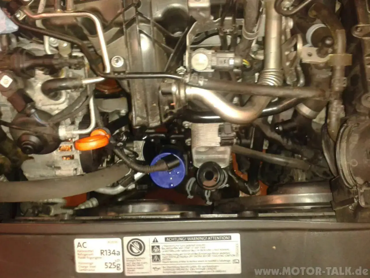 Anleitung zum Wechseln des Thermostats beim Golf 6 1.6 TDI. Motorraum mit sichtbarem Ölfilter und Kühlmittelbehälter.