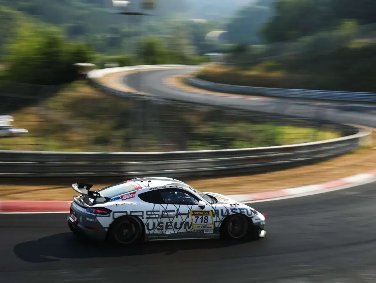 Ein Porsche GT4 RS mit der Startnummer 718 rast auf einer Rennstrecke durch eine Kurve.