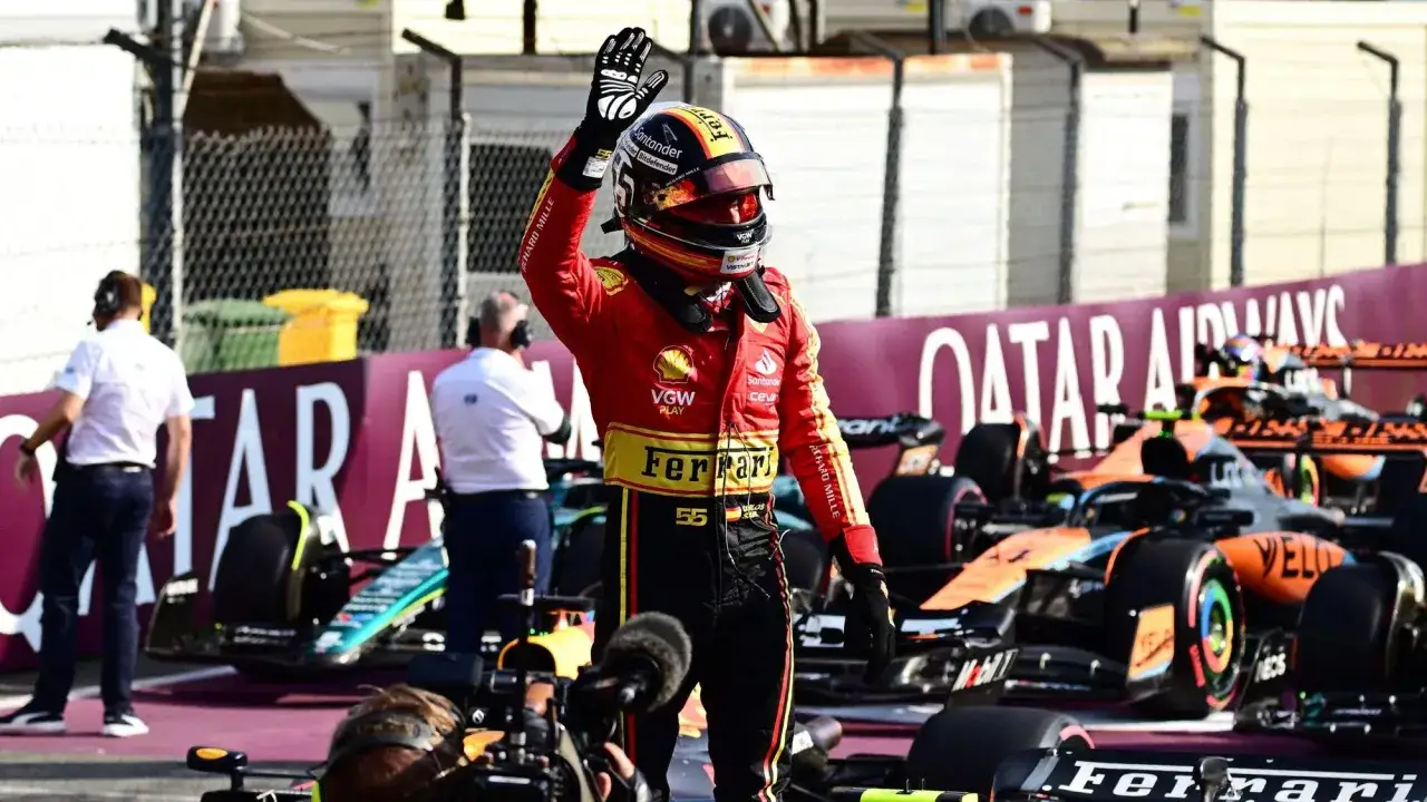 Carlos Sainz winkt nach der F1 Qualifying Monza. Hinter ihm stehen McLaren-Autos.