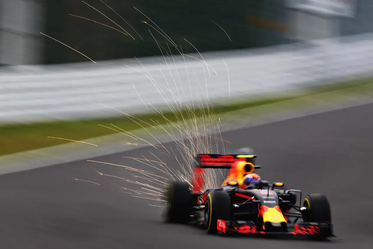 Formel 1 Rennwagen mit Funkenflug, der die extreme Beschleunigung auf der Strecke zeigt.