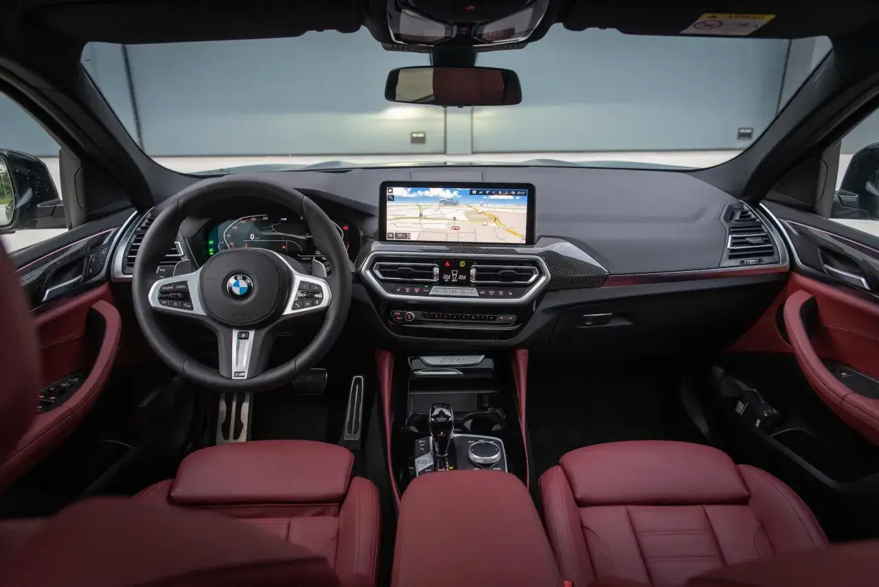 Innenraum eines BMW X4 30d mit roten Ledersitzen, großem Infotainment-Display und digitalem Cockpit. Technische Daten sind hier nicht ersichtlich.