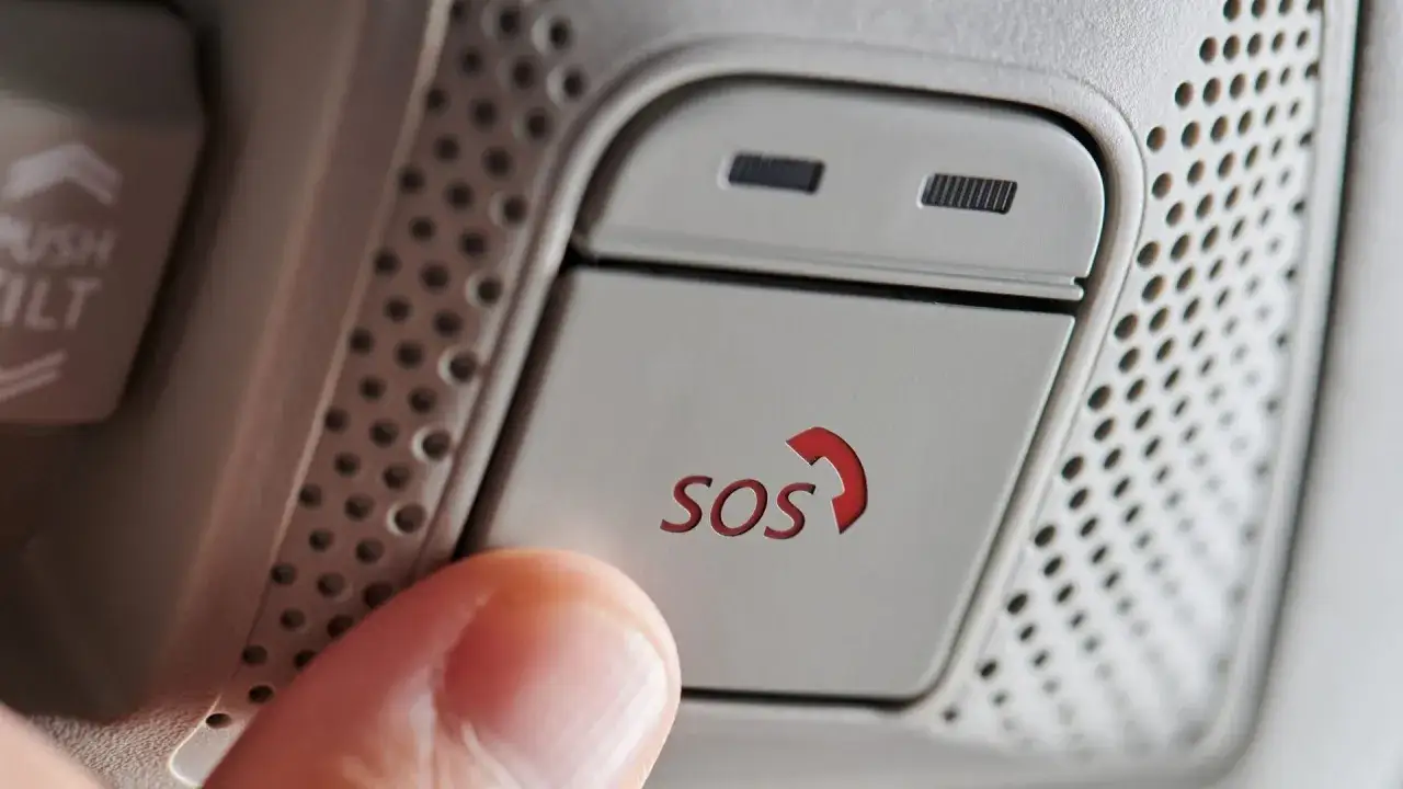 Daumen drückt SOS-Knopf im Auto. In welcher Situation eCall auslösen? Sicherheit geht vor.
