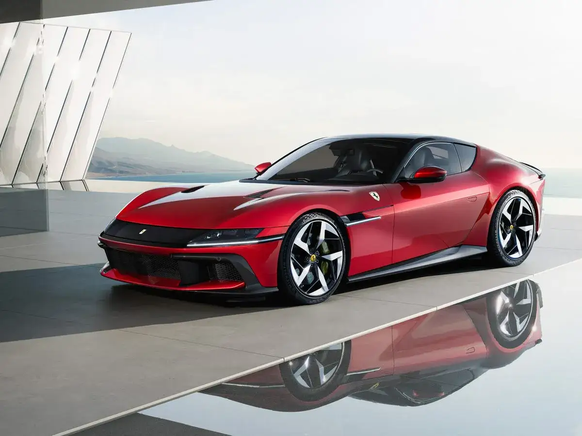 Roter Ferrari 12 Zylinder Sportwagen mit schwarzem Dach, elegant auf poliertem Boden, spiegelt sich im Wasser.