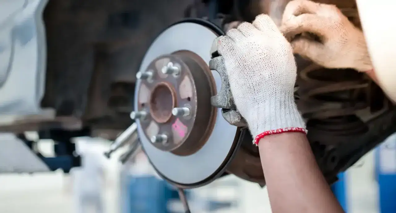 Mechaniker mit Handschuhen prüft die riefen bremsscheibe.