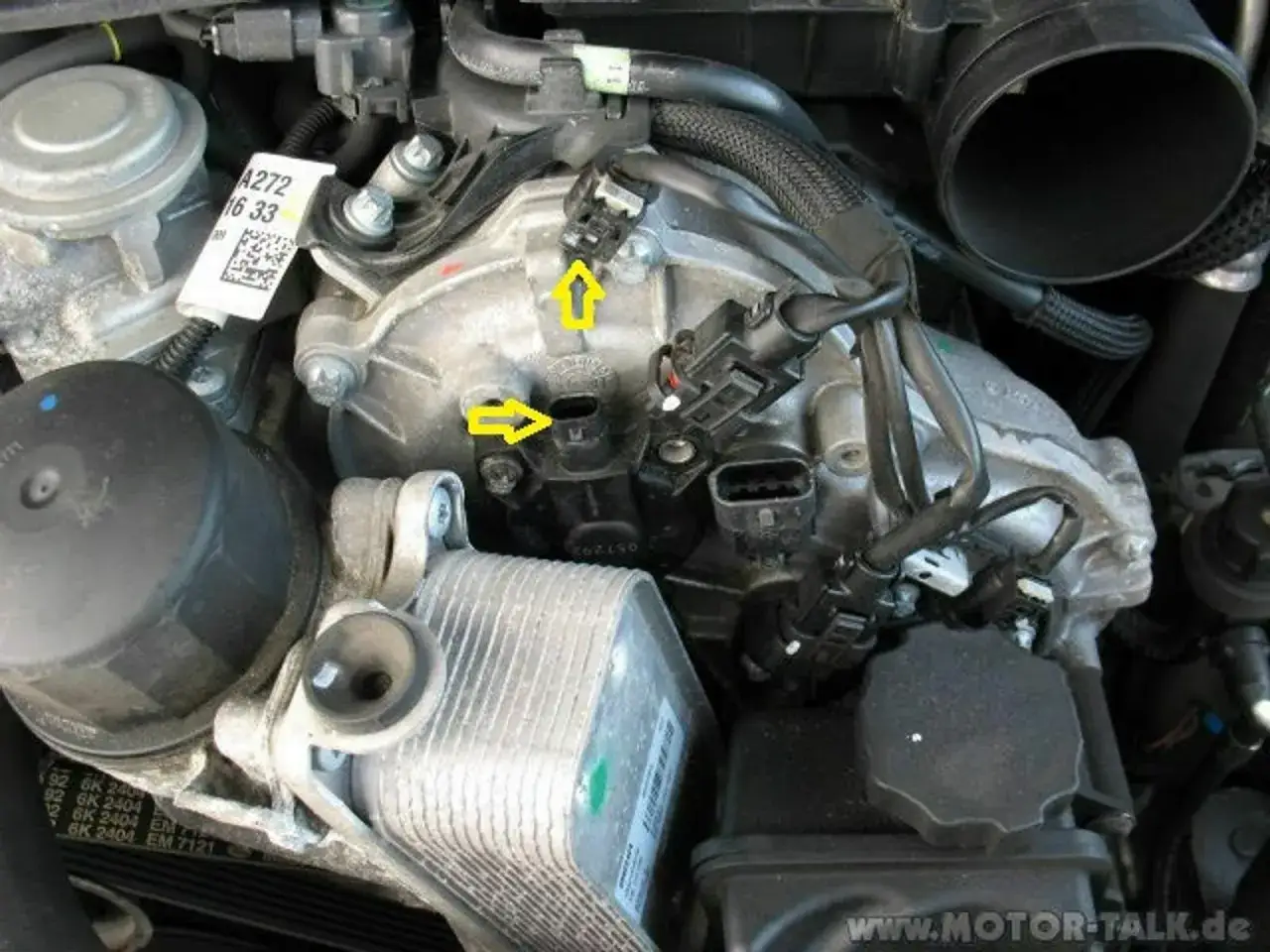 Mercedes-Benz Motorraum mit gelben Pfeilen, die auf die Nockenwellenversteller zeigen. Mögliche Ursache für DTC P0015.