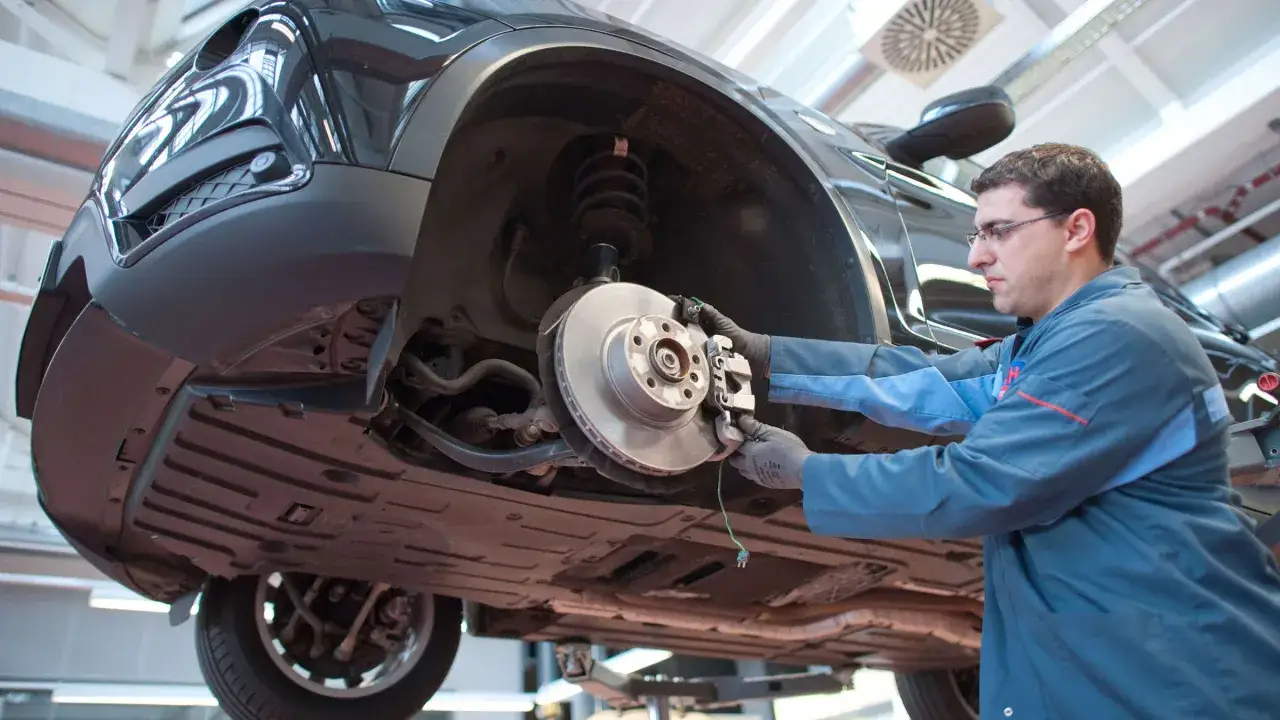 Mechaniker arbeitet am Bremssystem eines Autos. Bald werden die Bremsen quietschen, wenn sie nicht richtig repariert werden.