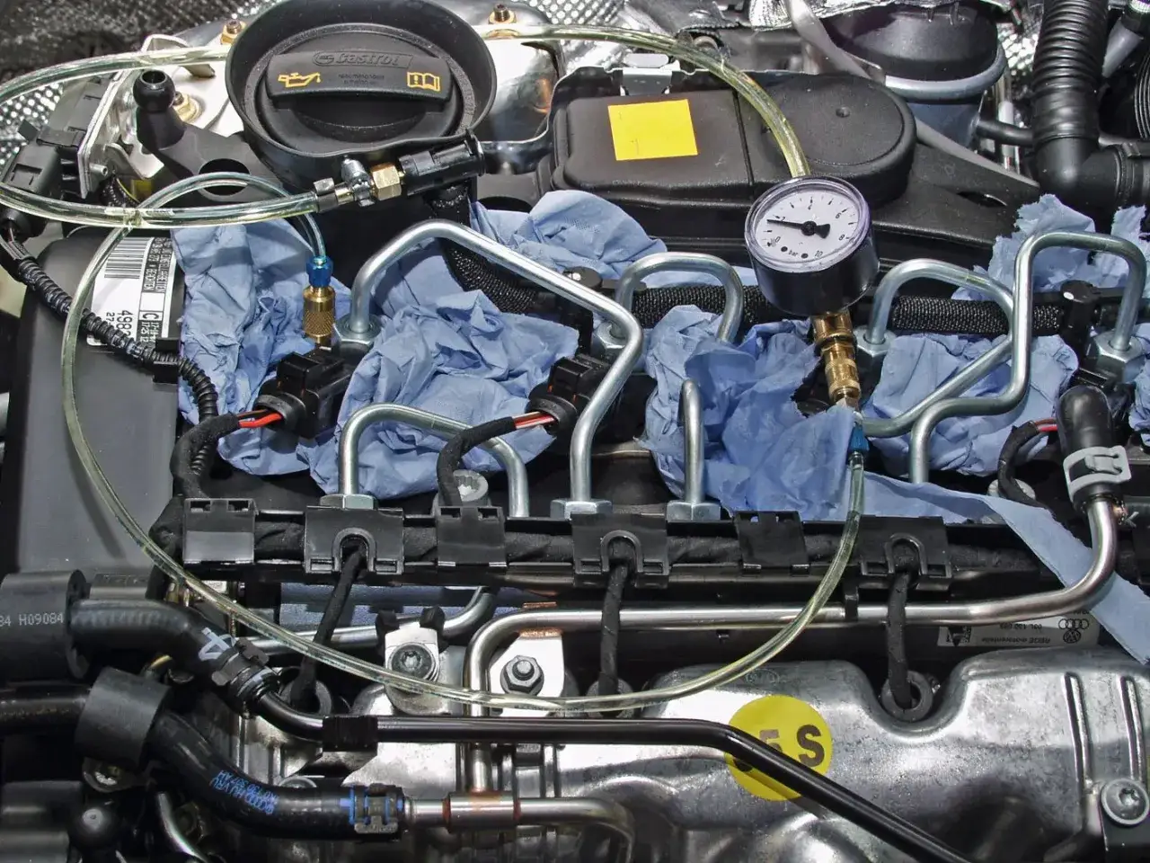 Detailaufnahme eines p0087 Mercedes Motors mit Druckmessgerät und Kraftstoffleitungen, bereit für eine Diagnose.