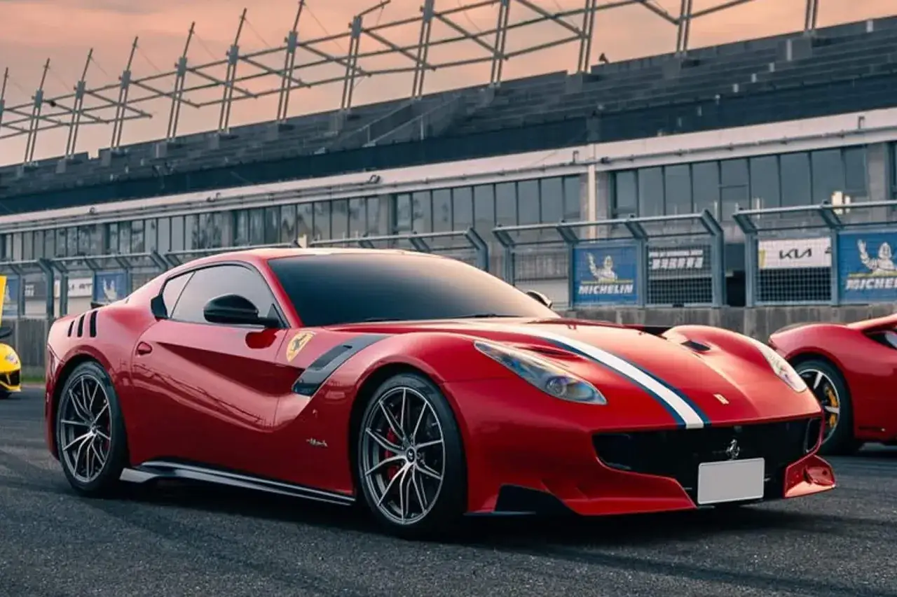 Roter Ferrari F12 TDF mit weißen und blauen Streifen auf der Rennstrecke, bereit für die nächste Runde.