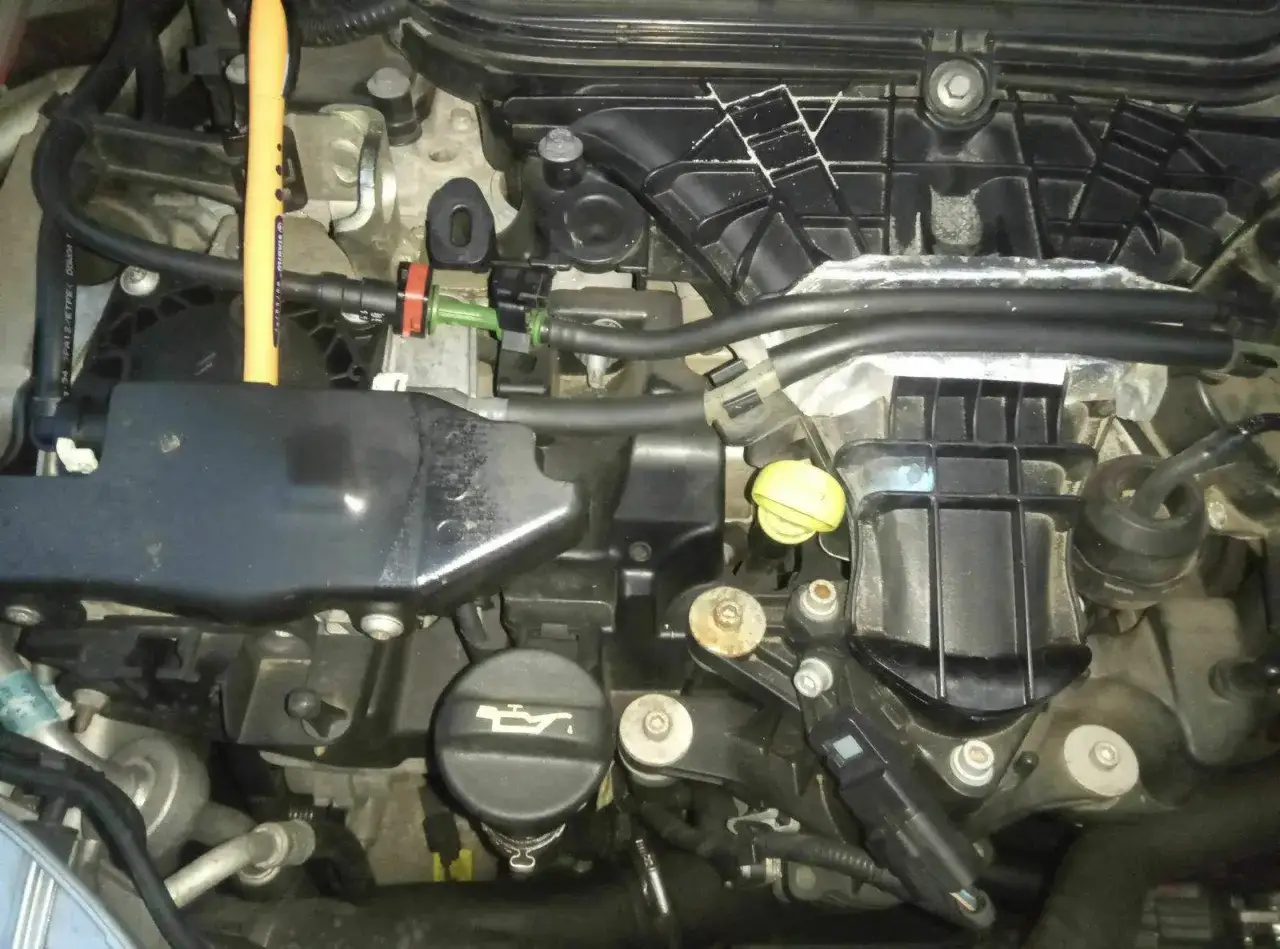 Motorraum eines Ford Kuga. Ein gelber Stift liegt auf dem Motorblock, nahe der Stelle, wo der Kraftstofffilter gewechselt wird.