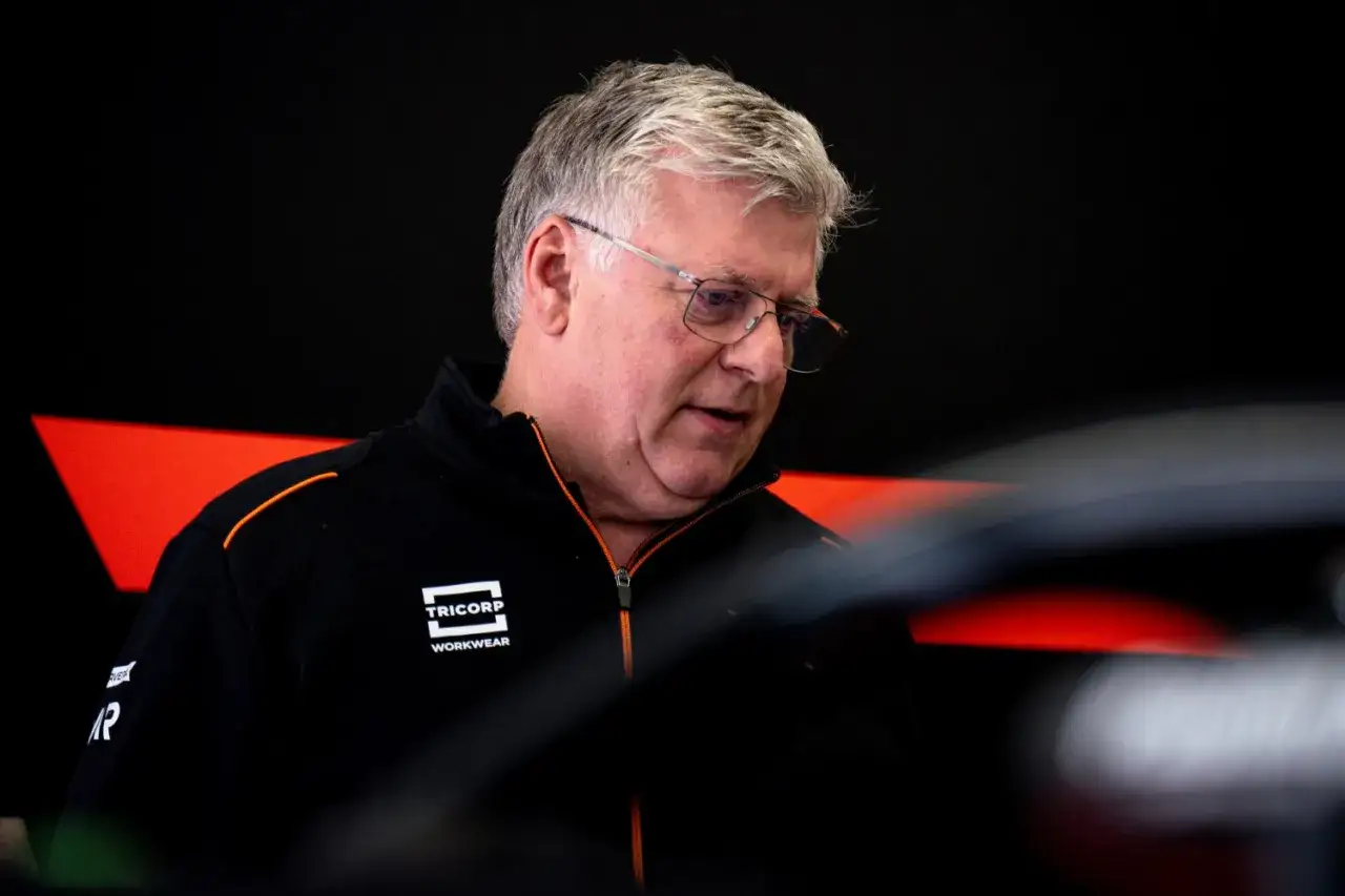 Otmar Szafnauer, mit Brille und schwarzer Jacke mit orangefarbenen Akzenten, konzentriert sich auf seine Arbeit.