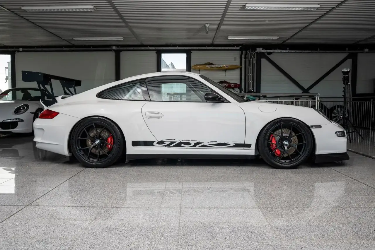 Weißer Porsche 997.1 GT3 RS mit schwarzem Heckspoiler und GT3 RS Schriftzug auf der Seite.