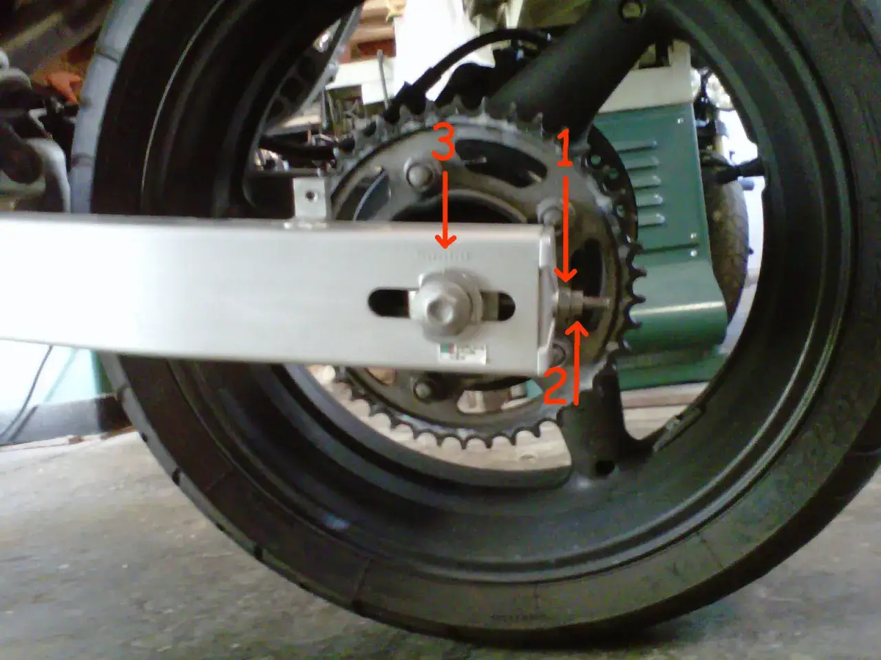 Motorrad-Kettenspannung: Pfeile zeigen die Einstellung der Kettenspannung am Hinterrad.