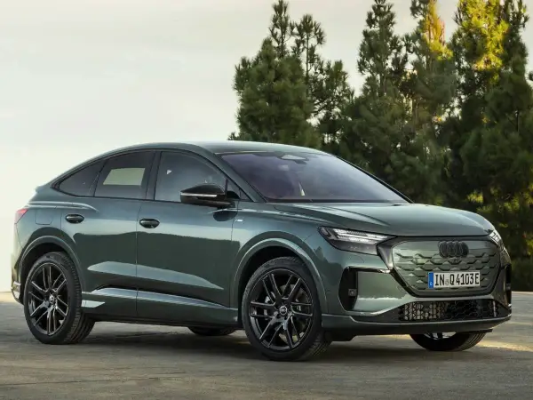 Der **Audi Q4 Facelift** in elegantem Grün steht vor Bäumen. Sein sportliches Design mit coupéhafter Dachlinie und markanten Felgen macht ihn zum Hingucker.